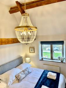 een slaapkamer met een bed en een kroonluchter bij HEBE COTTAGE - Idyllic and homely with attention to detail in Atworth