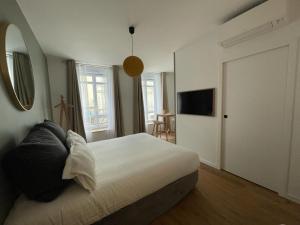a bedroom with a bed and a television and a door at Demeure Rossini Cholet Centre in Cholet