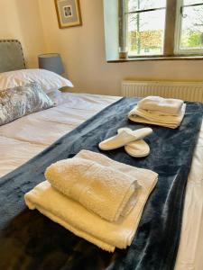 Una cama con dos toallas y dos zapatillas. en HEBE COTTAGE - Idyllic and homely with attention to detail en Atworth