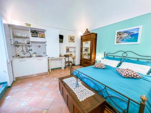 a bedroom with a blue bed and a kitchen at Amalfi Andrea's House in Amalfi