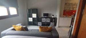 sala de estar con sofá gris y almohadas de color naranja en Apartamento Fibes y Congresos, en Sevilla