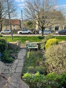a park bench in a garden with cars parked at HEBE COTTAGE - Idyllic and homely with attention to detail in Atworth