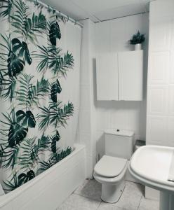 a bathroom with a toilet and a green leafy shower curtain at Apartamento en la playa in Salou