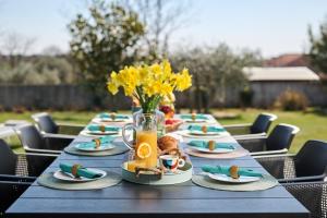 a long table with plates of food and a vase of flowers at Villa Frida in Zambratija