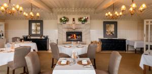 a restaurant with tables and chairs and a fireplace at Wharekauhau Country Estate in Wairarapa