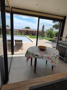a room with a table and a view of a pool at La Maison des Romarins Chambres d'hôtes Cosy Climatisées Piscine Cuisine in Aigremont