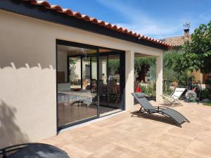 a patio with glass doors and a chair on a patio at La Maison des Romarins Chambres d'hôtes Cosy Climatisées Piscine Cuisine in Aigremont