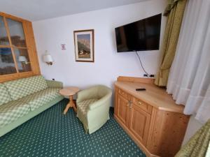 a room with a couch and a tv and a chair at Residence Riposo in Colfosco