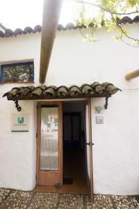 einen Eingang zu einem weißen Gebäude mit einer Holztür in der Unterkunft CASITA ESPERANZA in Alájar