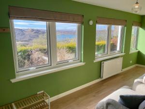 a green room with three windows and a couch at Smithy House in Tongue