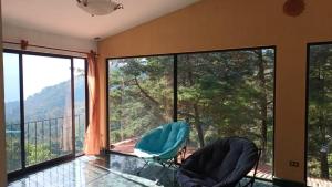 a room with two chairs and a large window at Hotel del Bosque in Guatemala