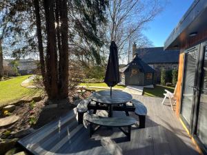 a patio with a table and an umbrella at Royal Snug & Wee Snug Cabins in Kincardine OʼNeil
