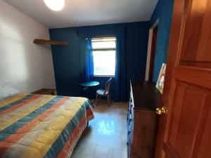 危地馬拉的住宿－Hotel del Bosque，一间卧室配有一张床、一张书桌和一个窗户。