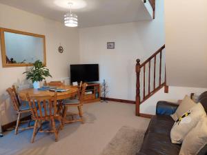 a living room with a table and a television at The Beehive - Self catering in the heart of the Forest of Dean in Whitecroft