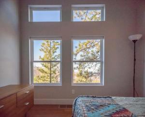 a bedroom with three windows with trees in the background at Aerial Ascent Yosemite in Yosemite West