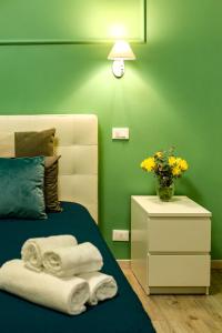 - une chambre verte avec un lit et un vase de fleurs dans l'établissement Lydka Domus, à Rome