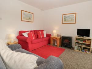 a living room with a red couch and a tv at Priory Ghyll in Windermere