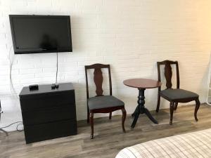 een kamer met 2 stoelen, een tafel en een tv bij Lakeside Inn in Orillia