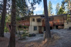 a large house with a deck in the woods at Sierra Springs in Oakhurst
