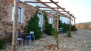 a brick building with tables and chairs and vines at Herdade Do Azinhal in Santa Clara-a-Velha