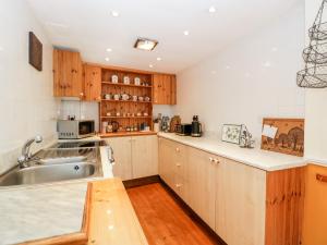 una cocina con armarios de madera y fregadero en The Pound en Trelleck