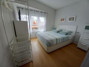 a white bedroom with a bed and a window at Apartamento Cabrales in Gijón