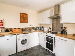 a kitchen with white cabinets and a washer and dryer at The Studio in High Catton
