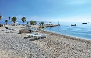 een strand met tafels en banken op een rotsachtig strand bij Amazing Apartment In Podstrana With Wifi in Podstrana