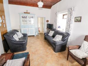 a living room with two leather chairs and a couch at The Cottage in Carrowsallagh Bridge