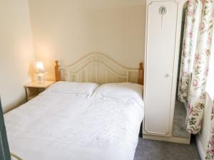 1 dormitorio con cama blanca y mesa auxiliar en The Cottage en Carrowsallagh Bridge