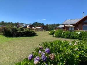 un jardín con flores púrpuras frente a una casa en Cabañas Copayapu, en Pucón