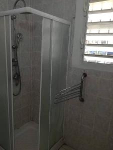 La salle de bains est pourvue d'une douche avec une porte en verre. dans l'établissement Studio meublé climatisé avec wifi à Desrochers Fort de France, à Fort-de-France