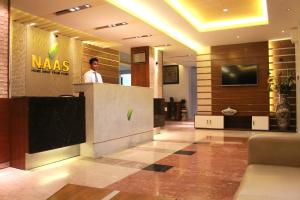 a man standing at a reception desk in a lobby at NAAS Serviced Apartments in Dhaka