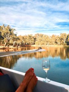 a person with their feet on a boat with a glass of wine at Eildon Parkview Motor Inn Room 9 in Eildon