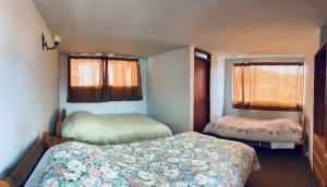 a small bedroom with two beds and two windows at Pampa Wasi in Cusco