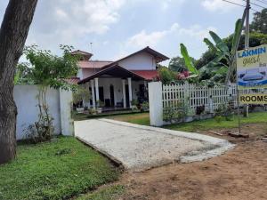 een huis met een wit hek en een oprit bij Lakwin guest wilpattu in Nekattegama