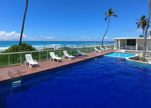 uma piscina com cadeiras e o oceano ao fundo em Areias do Mar ! Confortável e com Ar na Sala A315 na Barra de São Miguel