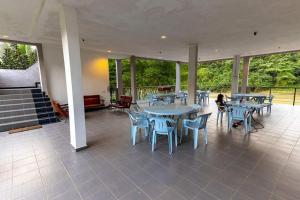 a large patio with tables and chairs and windows at RIVERSIDE PALM INN SG LEMBING in Sungai Lembing