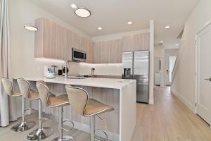 a kitchen with a counter with stools and a refrigerator at New Cozy & Spacious Townhouse near Disney - 4BR, 3FB, and Pool in Orlando