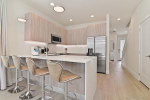 a kitchen with a counter with stools and a refrigerator at New Modern & Spacious Townhouse near Disney in Orlando