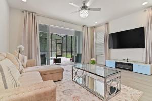 ein Wohnzimmer mit einem Sofa und einem TV in der Unterkunft New Modern & Spacious Townhouse near Disney in Orlando