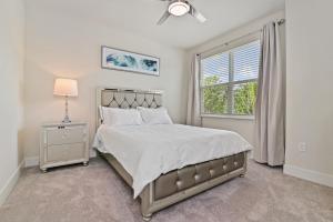 a white bedroom with a bed and a window at New Cozy & Spacious Townhouse near Disney - 4BR, 3FB, and Pool in Orlando +17 photos
