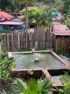 a pool of water in a yard with a wooden fence at RIVERSIDE PALM INN SG LEMBING in Sungai Lembing