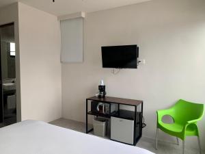 a bedroom with a bed and a tv and a green chair at Las Palmas Studios in Cancún