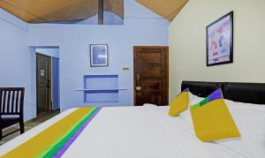 a bedroom with a large white bed with colorful pillows at Itsy By Treebo - Allaranda Homestay With Valley View in Madikeri