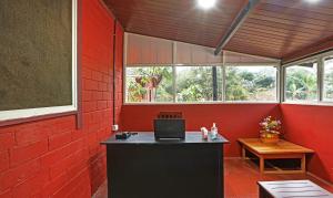 Cette chambre rouge comprend un bureau avec un ordinateur portable. dans l'établissement Itsy By Treebo - Allaranda Homestay With Valley View, à Madikeri