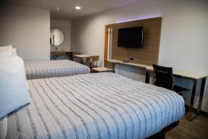 皮科里韦拉Pico Rivera Inn and Suites的有两张床和一张书桌的酒店房间