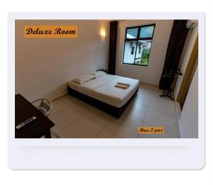 a bedroom with a bed and a desk and a window at RIVERSIDE PALM INN SG LEMBING in Sungai Lembing