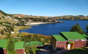 a house with a green roof next to a lake at Reserva del Arrayan in Tota