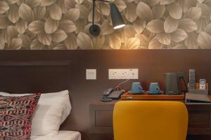 a bedroom with a yellow chair and a desk with a phone at East Riverine Boutique Hotel in Kuala Lumpur